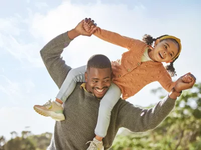 Father carrying daughter on shoulders and laughing